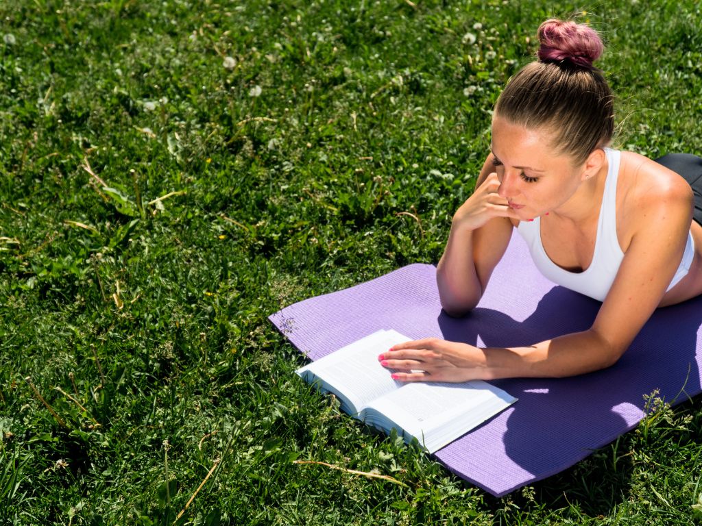 una-donna-legge-libro-Yogananda-sdraiata-sul-tappetino-yoga